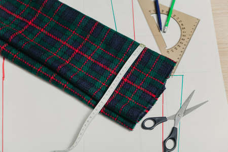 Still life on the sewing pattern. On the paper sheet drawn silhouette of a garment. On top is a...