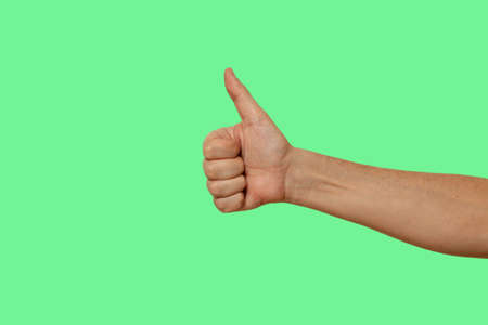 international symbol is good. Bare hand with thumbs up on isolated on green chroma key background. Four fingers bent into a fistの写真素材