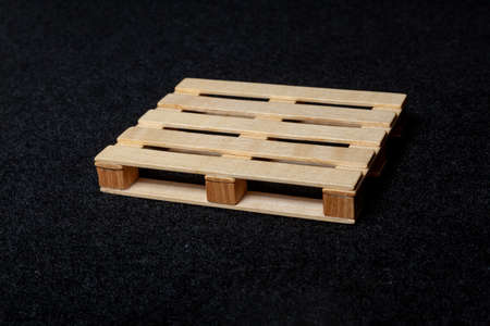 Mini version wooden pallet euro type souvenir toy on black felt backgroundの写真素材