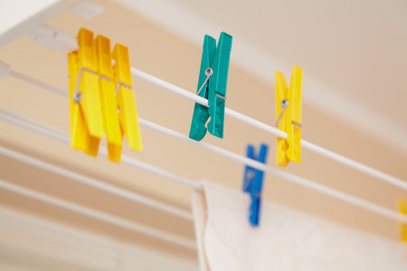Yellow and green plastic clothespins hanging on a modern dryer in the bathroom close-upの写真素材