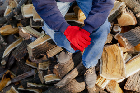 man in red gloves sits on a pile of mulberry tree firewood. View from aboveの写真素材