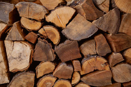background from wooden logs. Chopped firewood from different trees are densely stacked in several layers close-upの写真素材