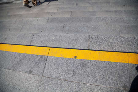 Step attention. A wide yellow warning strip is drawn on the stone rung of the city staircaseの写真素材