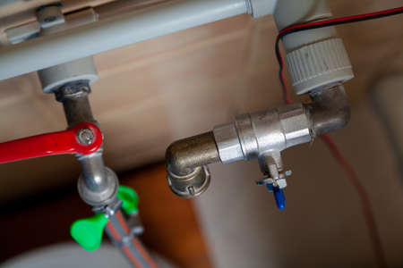Two ball valves of different designs are perpendicularly mounted on gray plastic pipes. View from aboveの写真素材
