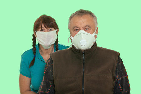 Security during a pandemic. Elderly family couple in white protective masks isolated on green chroma key backgroundの写真素材