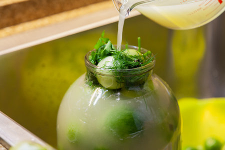Canned tomatoes at home. Muddy pickle is poured into a glass jar with green tomatoes close-upの写真素材