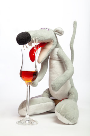 symbol of 2020, a cute gray rat with a long tail sits on a stack of books on a white background close-up. A large red tongue inserted into an elegant glass cup with a long stemの写真素材