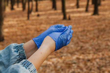 Prevention of infection. Man takes off blue rubber latex disposable gloves in autumn forest close upの写真素材