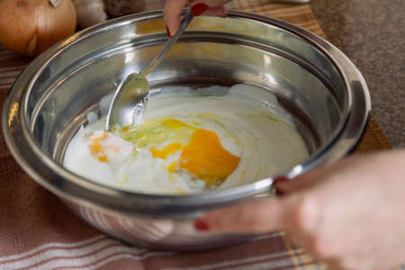 Female hands stir fresh eggs with kefir with a spoonの写真素材