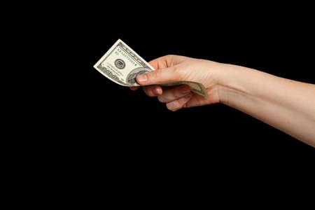 Currency on the black market. The right hand holds a hundred dollar bill on a black backgroundの写真素材