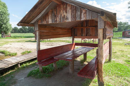 Gazebo in nature. A wooden gazebo stands on the shore of the reservoir. Inside there is a wooden table and benchesの写真素材