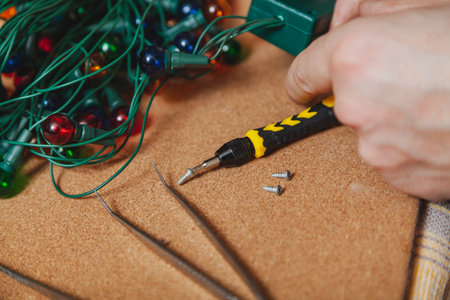 Preparing for the New Year. Repair of a Christmas tree electric garland. Screwdriver holding a small screw close-upの写真素材