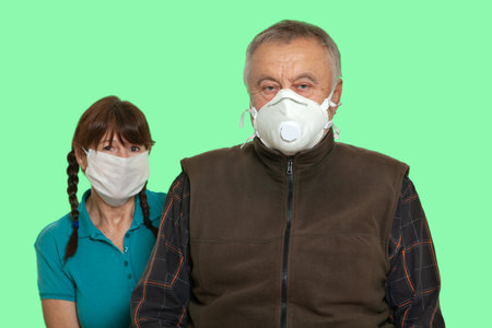 Security during a pandemic. Elderly family couple in white protective masks isolated on green chroma key backgroundの写真素材