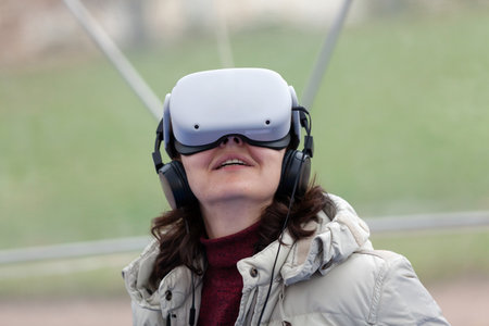 virtual reality session. A woman in a light jacket uses a virtual reality headset and smiles prettyの写真素材