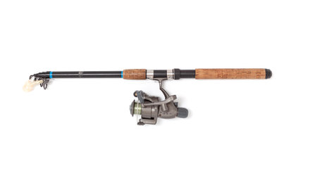 A folded telescopic spinning rod lies on a white background. A gray inertialess reel is fixed on it with a fishing line and a twisterの写真素材