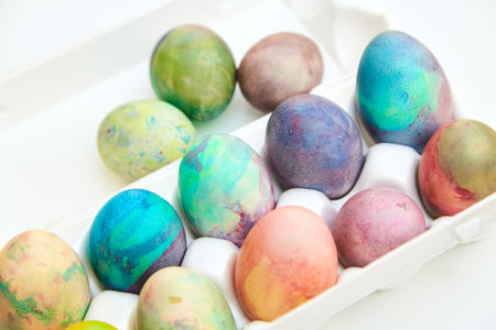 Attribute Easter holiday. Several chicken eggs originally painted in different colors are in a plastic container with cells. Nearby are three eggsの写真素材