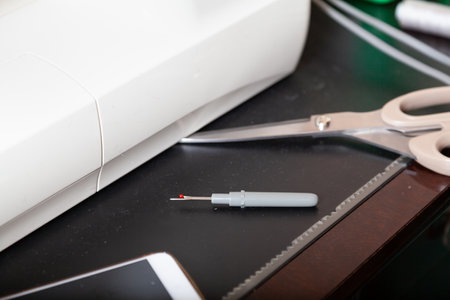 Unusual sewing tool. Seam ripper and scissors lie on a black surfaceの写真素材