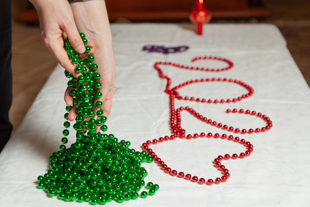 Woman hands laying a long green garland of small balls on a white table close-upの写真素材