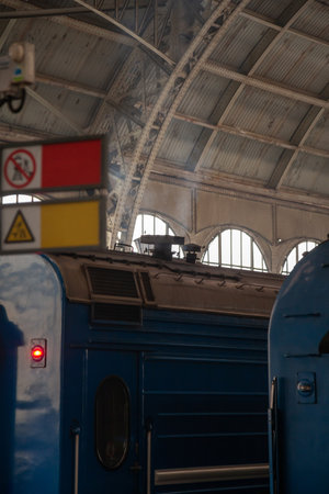 A passenger train car stands under the dome of a covered platform at the railway station station. White smoke from stove heating is visible above the roofの写真素材
