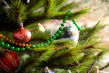 A garland of small green balls hangs on the branches of a Christmas tree. colorful toys hanging nearbyの写真素材