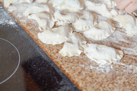 Some raw dumplings in white flour lie on a granite countertopの写真素材