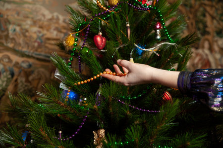 We disassemble the Christmas tree. Hands remove a yellow garland of small balls from a green spruce branch close-upの写真素材