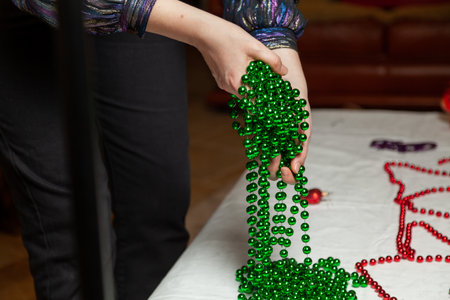 Woman hands laying a long green garland of small balls on a white table close-upの写真素材