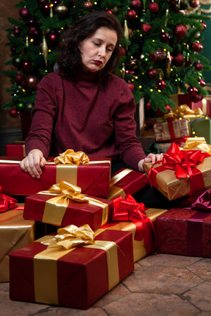 Tired of preparing for the new year, a woman sleeps sitting against the background of a decorated Christmas tree and giftsの写真素材