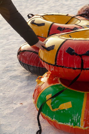 Intention to go tubing on a winter day from a mountain in the snow. A man hand holds one of the tubes by the handleの写真素材