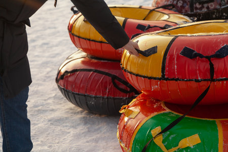 Intention to go tubing on a winter day from a mountain in the snow. A man hand holds one of the tubes by the handleの写真素材