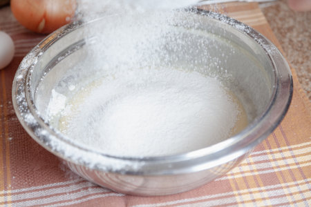 Sifted flour is poured into a metal bowl on a napkinの写真素材