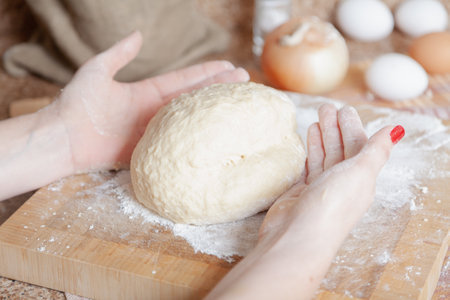 A piece of dough on a square board and women hands above itの写真素材
