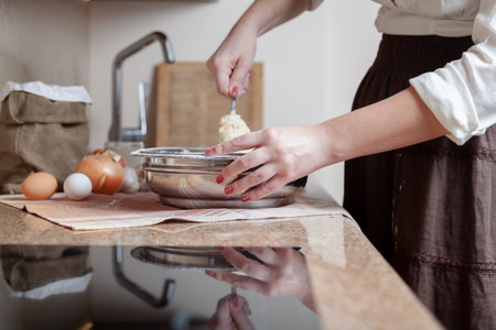 A woman in a dark skirt mixes dough in a bowl with a spoonの写真素材