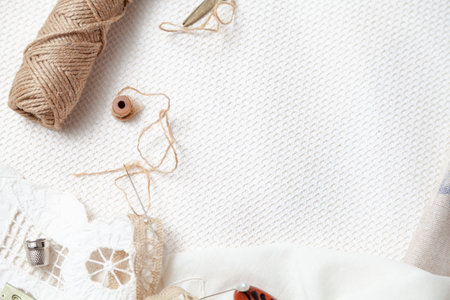 A roll of rope lies on a cotton fabric with a checkered texture. Nearby lies a steel thimble and a needle. View from above. In the center there is a place for the descriptionの写真素材