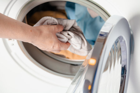 Hands putting dirty laundry in a front-loading washing machine. Close-upの写真素材