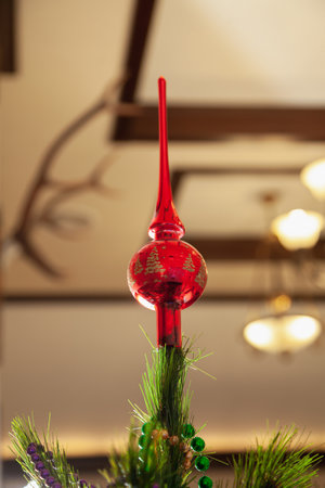Red glass top on a Christmas tree close-up. Defocused chandelier in the backgroundの写真素材