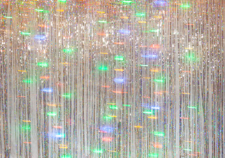 Photo zone for a Christmas party. Background for photography from silver tinsel and blurry lights of a luminous garland at a long exposureの写真素材