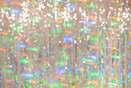 Defocused image of bokeh reflections from Christmas tinsel. Long exposure blurry green garland lightsの写真素材