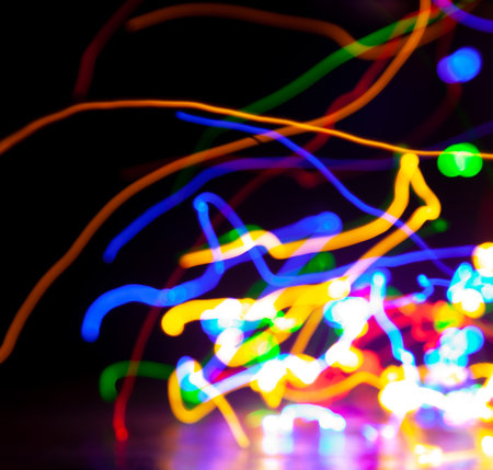 Abstract frozen image of moving multi-colored electric lights on a dark background on a smooth surface. Photo created using a long exposureの写真素材