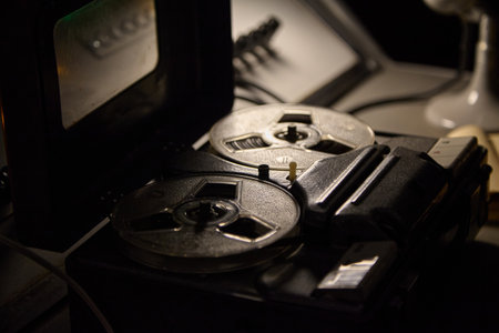 in a dark, gloomy, classified office stands a vintage tape recorder with two reels of audio...