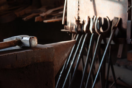 Anvil and hammer in a village forge in the light from the window, other blacksmith tools in the...