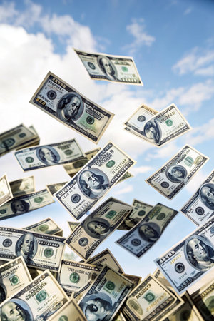 Dollar banknotes flying in the blue sky with white clouds.の素材