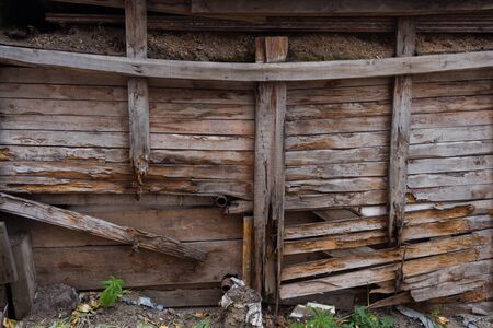 A ruined wall of wooden planks and posts.