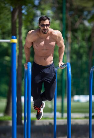 athlete doing pull-up on horizontal bar.Mans fitness outdoor