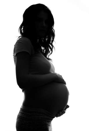 shadowed pregnant woman.Studio shot isolated on whiteの写真素材