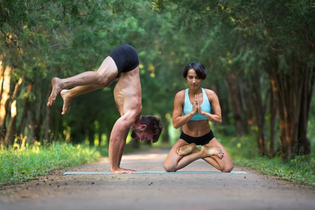 Acro yoga, two person practice yoga in pair, couple doing stretching exercise in the garden