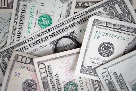 A pile of Five, Ten and One hundred US dollar bills on a table