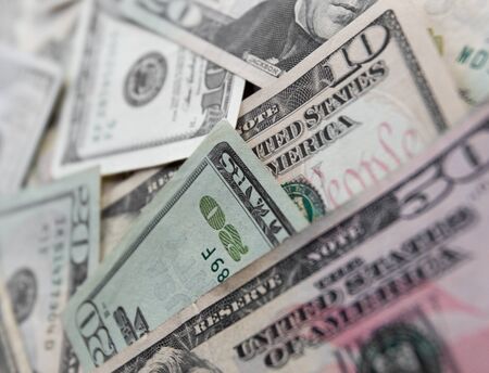 A pile of Five, Ten and One hundred US dollar bills on a tableの写真素材