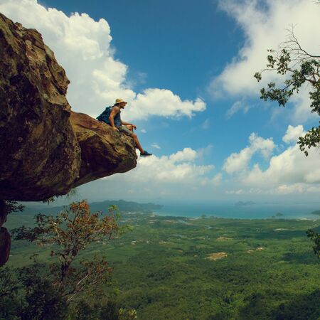 Hiker sits on a cliffの写真素材