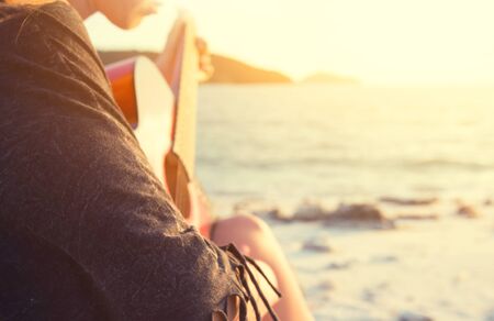 woman playing guitar on sunset beachの写真素材